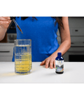 Woman mixing Fulvic Ionic Minerals X350 into water, showing the transformation of the liquid and ease of incorporating it into daily routines.