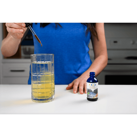 Woman mixing Fulvic Ionic Minerals X350 into water, showing the transformation of the liquid and ease of incorporating it into daily routines.