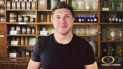 Man standing in front of vintage apothecary shelves, promoting Fulvic Ionic Minerals X350 by Optimally Organic for health and wellness.