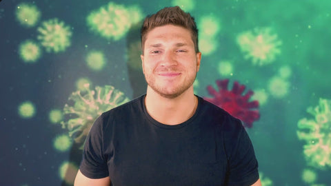 Man smiling in front of a green background with virus-like illustrations, representing health and immune system focus.