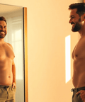 Fit man smiling in front of a mirror, showcasing weight loss and body transformation with Weight-loss Accelerator Extract.